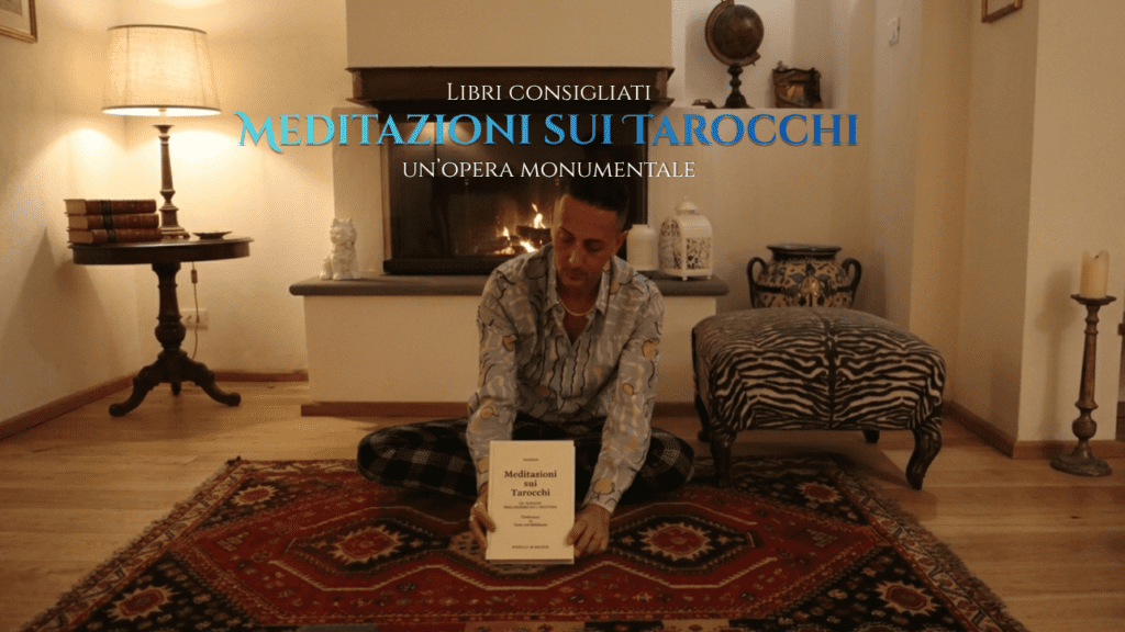 Un uomo seduto a terra in una stanza accogliente mentre tiene in mano il libro "Meditazioni sui Tarocchi"